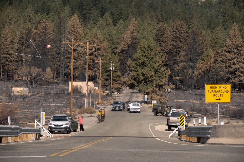 Fire crews walking as trucks and people are parked nearby